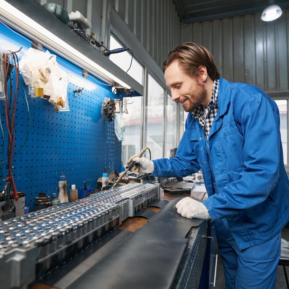 Smiling man inspecting car parts in garage